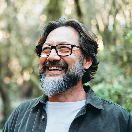 Man with a beard and glasses smiling outdoors